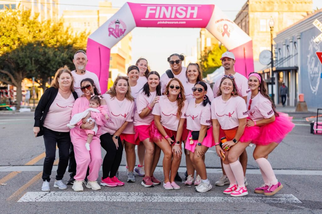 A team in pink posing under the finish arch