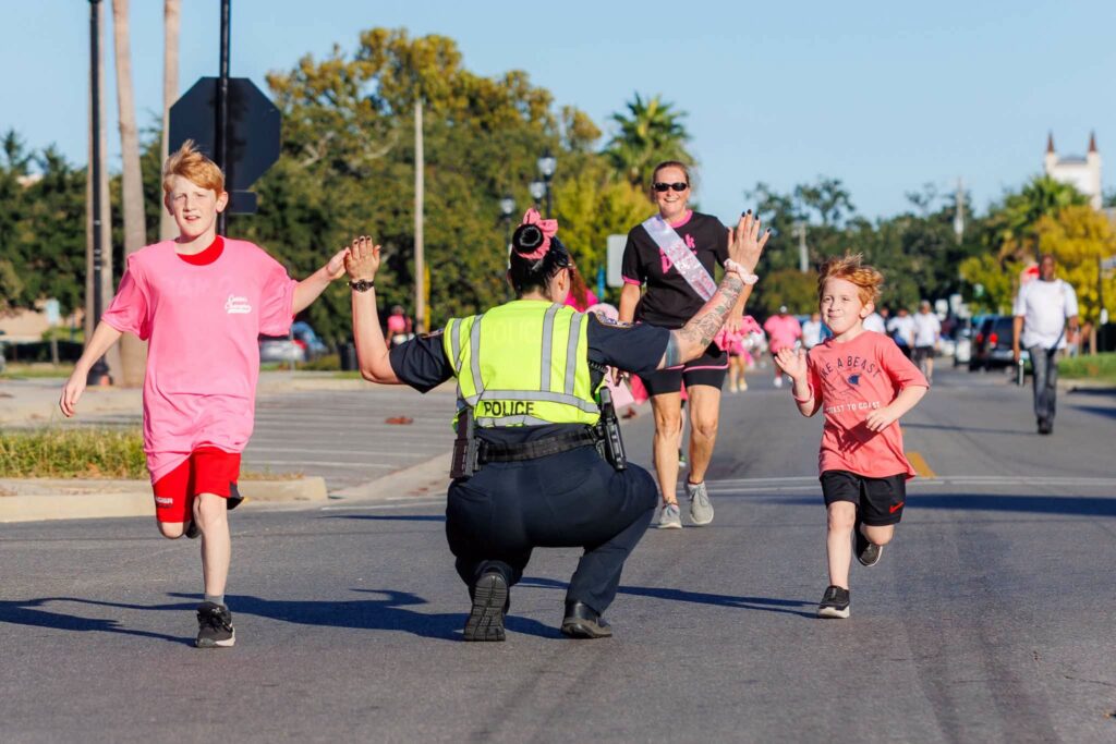 A police officer high-fiving a young runner
