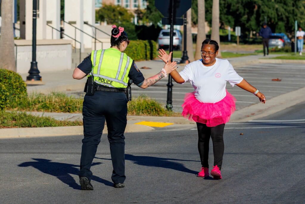 A walker in a pink tutu high-fiving an officer